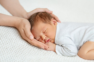 Baby Head in Mother Hands. Mum Love. Sleeping Newborn in Parent Palms over White Blanket. Infant...