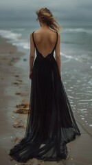 Fototapeta na wymiar fine art rear view of woman in classic black dress on beach near ocean