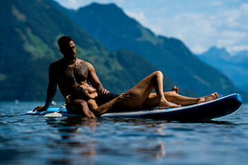 Sexy summer couple. Couple paddling in nature. Sensual fit sexy lovers on sup board paddle surfing....