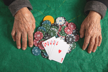 Elderly female hands holding casino games chips and cards.