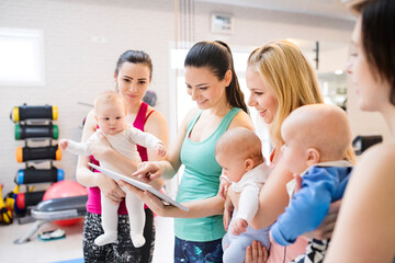 Instructor scheduling the next group exercise class. Moms staying active, working out with baby in...