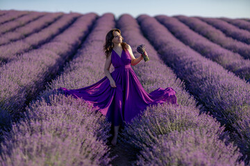 A woman in a purple dress is standing in a field of lavender. She is holding a bouquet of flowers and she is enjoying the beauty of the flowers. Concept of serenity and appreciation for nature.