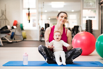 Naklejka premium Portrait of new mom on group exercise class in gym. Moms staying active while boding with babies.