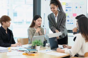 Asian group of people working with documents have financial or marketing charts on a board room table at a business presentation or seminar.