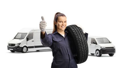 Woman mechanic worker carrying a van tire and gesturing a thumb up sign