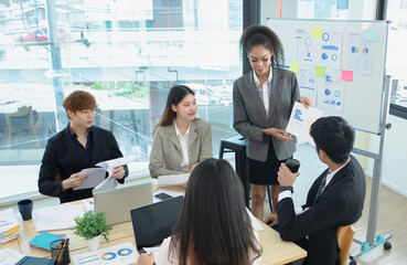 Asian group of people working with documents have financial or marketing charts on a board room table at a business presentation or seminar.