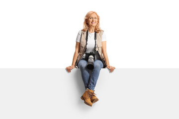 Female photo journalist sitting on a blank panel - obrazy, fototapety, plakaty