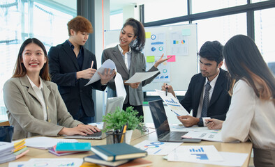 Asian group of people working with documents have financial or marketing charts on a board room table at a business presentation or seminar.