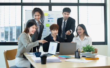 Asian group of people working with documents have financial or marketing charts on a board room table at a business presentation or seminar.