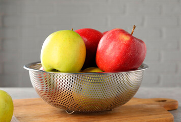 Fresh ripe apples in colander on table, closeup