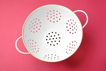 One clean empty colander on pink table, top view