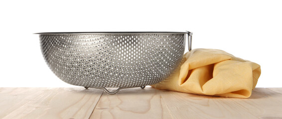 Metal colander and napkin on wooden table against white background