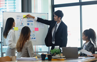 Group of asian business people working and brainstorming in workshop and analyzing marketing reports startup project infographics in the office, Sales and business plans, presentation ideas concept.
