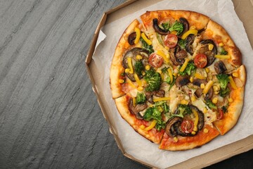 Delicious vegetarian pizza with mushrooms, cheese and vegetables in box on black table, top view. Space for text
