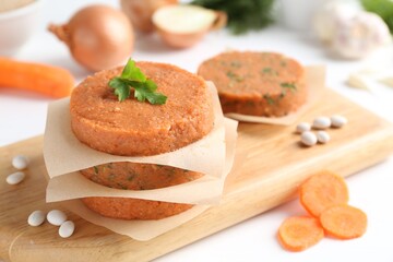 Uncooked carrot cutlets and ingredients on white wooden table, closeup. Vegetarian product