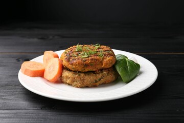 Vegetarian product. Tasty carrot cutlets, vegetable and basil on black wooden table