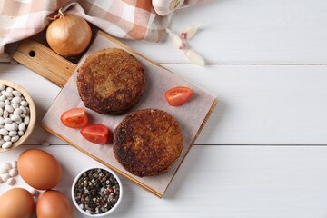 Vegetarian product. Tasty bean cutlets served on white wooden table, flat lay. Space for text