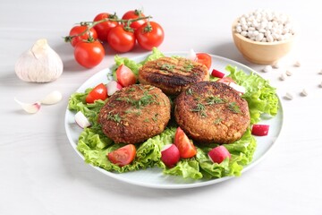 Delicious vegetarian cutlets and vegetables on white table