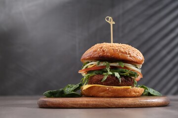 Board with delicious vegetarian burger on grey table. Space for text