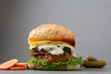 Delicious vegetarian burger and ingredients on grey wooden table