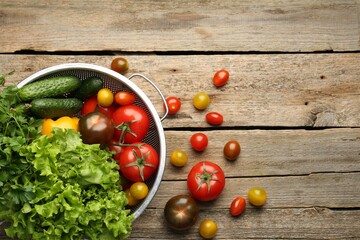 Fresh vegetables in colander on wooden table, flat lay. Space for text