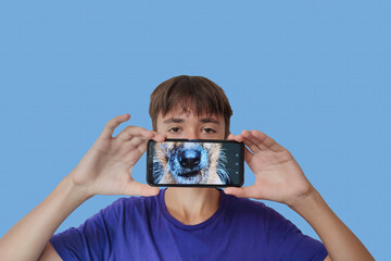 Portrait of a young guy with a smartphone in his hands, image of a dog on the smartphone