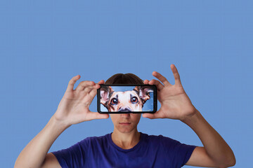 Portrait of a young guy with a smartphone in his hands, image of a dog on the smartphone