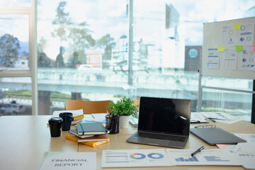 Laptop at office desk, graphs and charts, analysis report chart in office workspace.