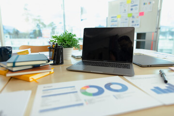 Laptop at office desk, graphs and charts, analysis report chart in office workspace.