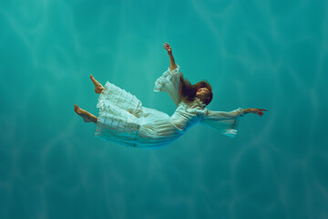 Serene underwater moment with elegant young girl in tender white dress levitating with calm expression underwater with sunlight above. Concept of surrealism, beauty, mystery and fantasy, freedom