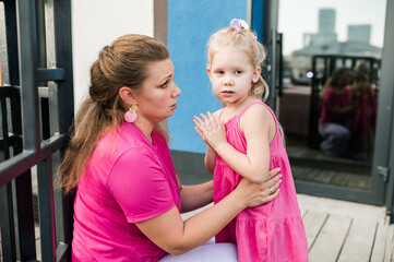 Deaf child with cochlear implant for hearing audio and aid for impairment having fun and laughs with mother outdoor in summer. Sound fitting device to help with communication listening and interaction