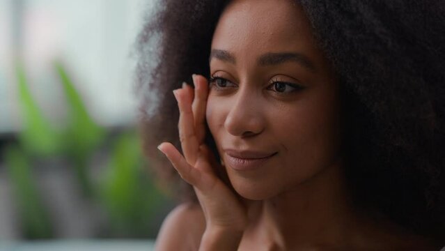 Beauty skincare procedure pretty beautiful smiling woman African American girl female skin care touch face cream moisturize cosmetic facial massage cheeks dark circles under eyes wrinkles protection