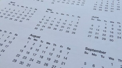 Closeup of different months and dates of a personal calendar sheet. Organizing time, meeting,...