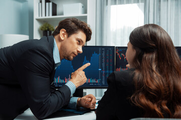 Two business traders discussing on dynamic stock market in currency rate investment trading on two...