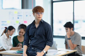 Fototapeta premium Asia young creative man in smart casual wear looking at camera in office workplace.
