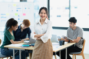Fototapeta premium Asia young creative people in smart casual wear looking at camera in office workplace.