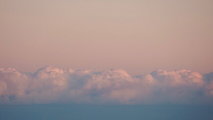 Fluffy clouds sunset sky above calm sea with space for text. Miminal coastal banner.