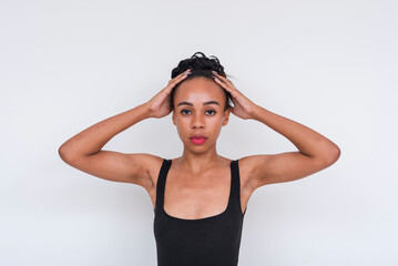 Confident mixed race woman in a black bodysuit posing against a white background
