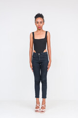 Confident mixed-race woman in a black bodysuit and jeans on a white background