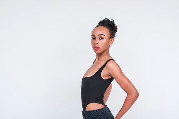 Confident young woman of mixed African and Asian ancestry in black bodysuit posing against a white backdrop