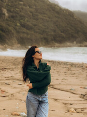 A woman in a green sweater on the beach. Corsica. France