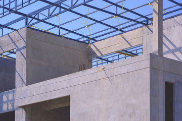 Incomplete bare concrete room wall with electrical conduit wiring system on roof beam outline on top of modern office building structure in construction site