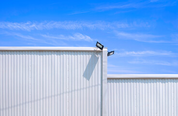 Two white aluminium corrugated steel warehouse building in modern minimal style with LED spotlights...