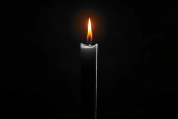A tall candle burning with a soft light on a dark background