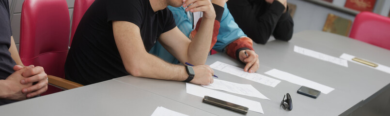 Higher education students sitting thoughtfully at a desk during a lesson, study session, lecture,...