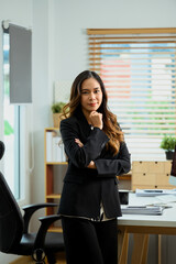 Portrait of attractive young businesswoman standing in her office and looking at camera