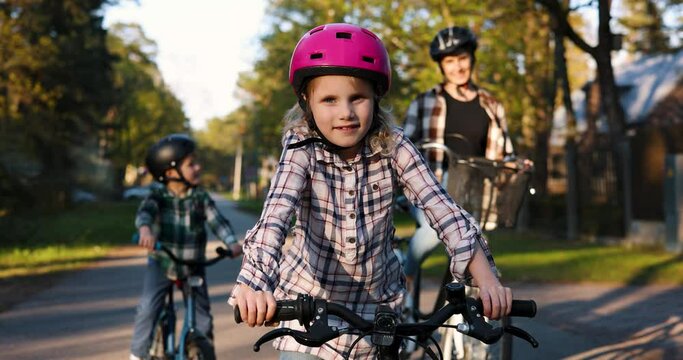 little girl with pink helmet together with family standing on bicycles and are ready for cycling
