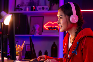 Host channel of smiling beautiful Asian girl streamer playing online game wearing headphone talking...