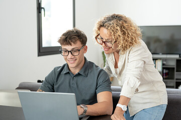 Young smiling boy studies at home with the support of a personal tutor using laptop. Blonde teacher...