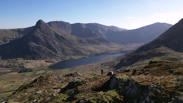 An aerial reveal of a man and tent on a beautiful mountain landscape in Snowdonia